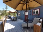 Deck furnished with table, chairs, umbrellas, lounger, and gas grill 